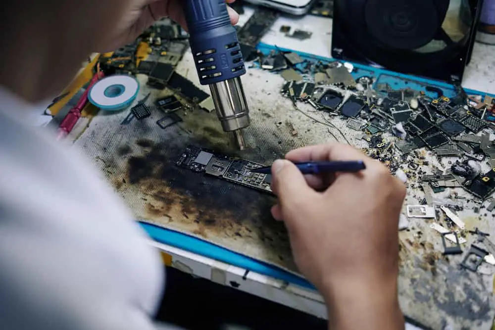 A technician using a hot air gun for repairs