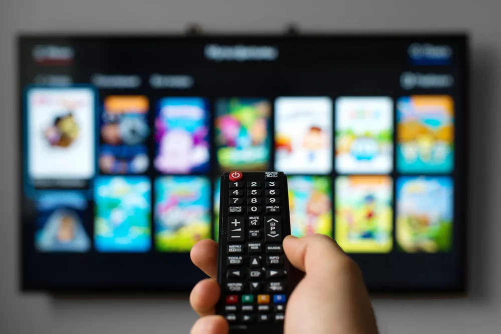 A man holding a remote to a smart TV