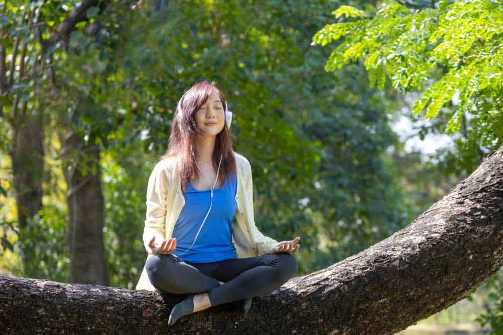 Ambient Sound vs. Noise Cancelling:Lady meditating with headphones on