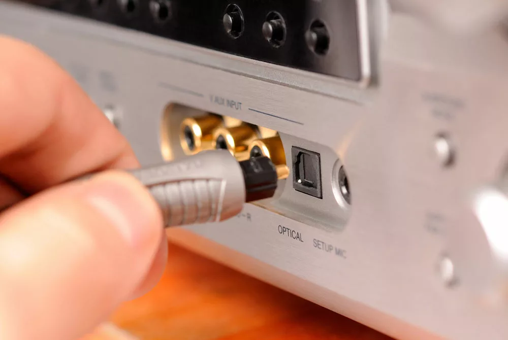 A man inserting the cable into an optical input