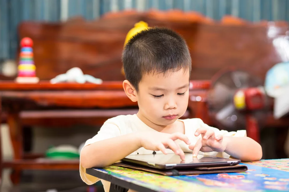 A kid touching an iPad tablet and playing game