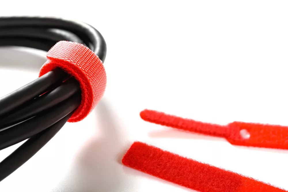 Red velcro fabric cable tie on black cables on white background