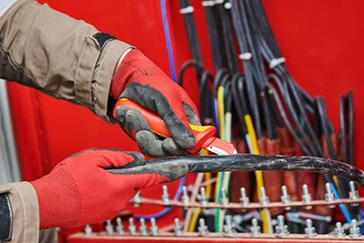 Electrician cutting cable insulation using a wire skinning knife.