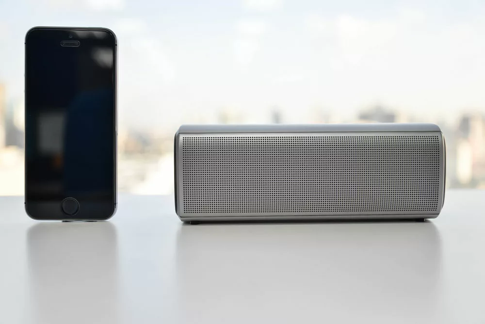 Portable speaker and a mobile phone on a white background