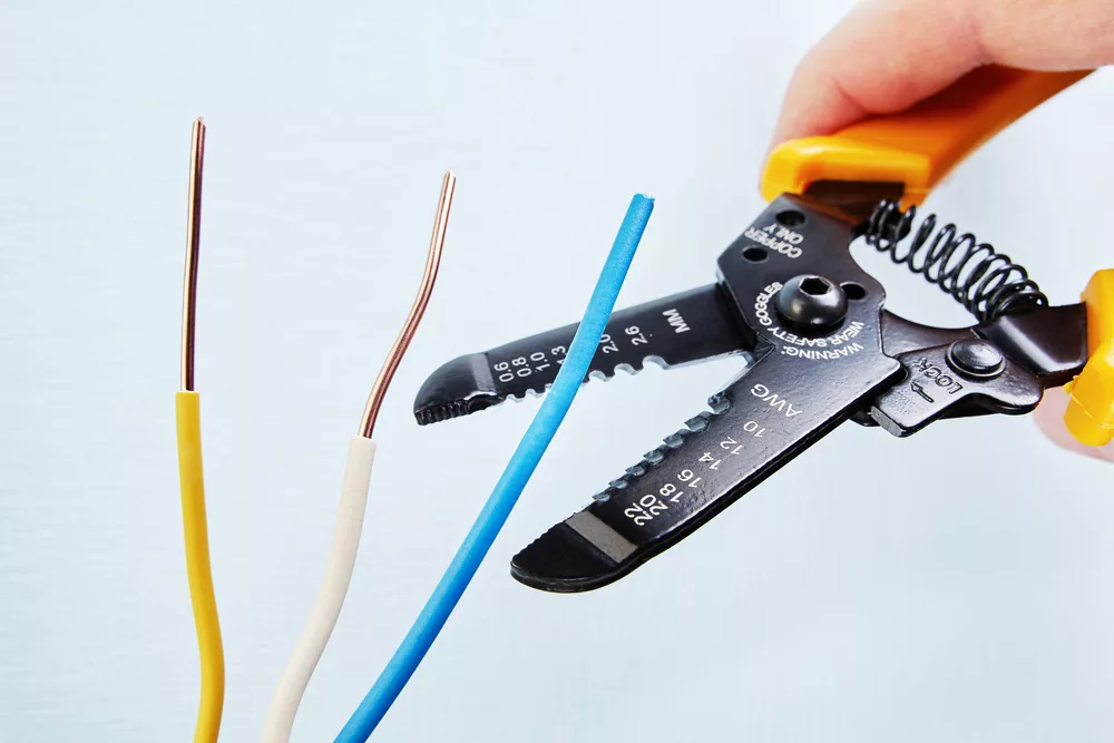 Electrician stripping a wire using a wire stripper