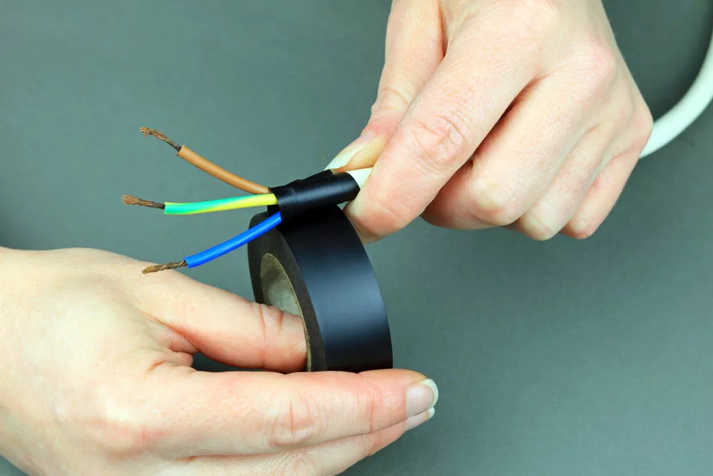 Hands applying electrical tape on a cable