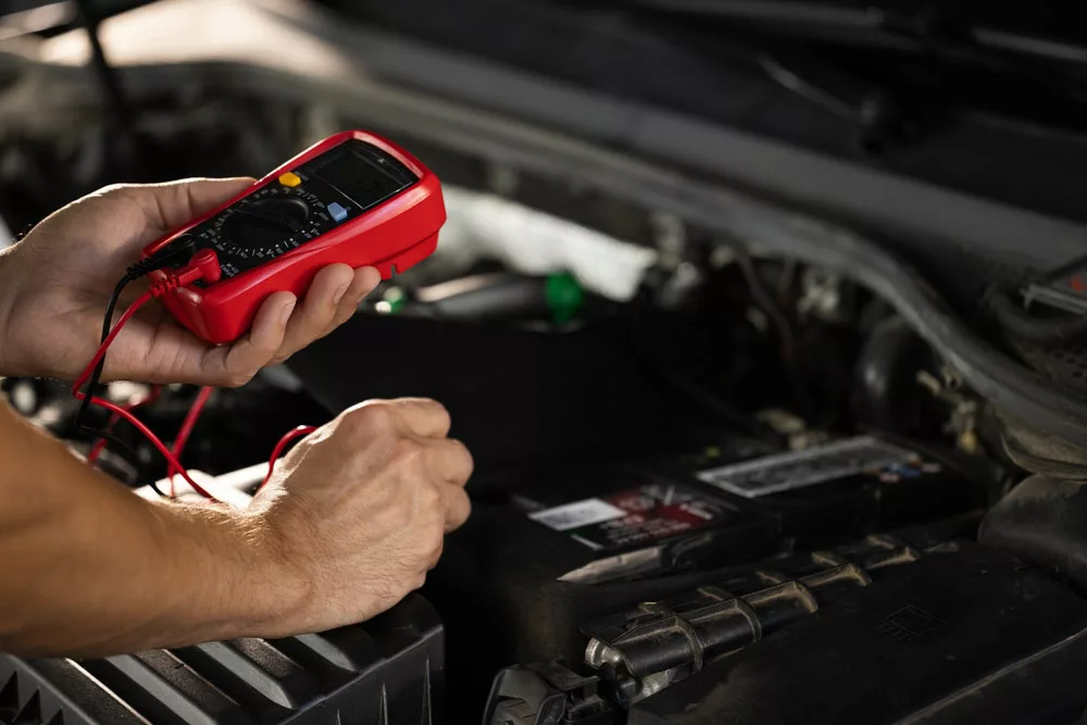 Battery Cable Loose: Mechanic checking voltage in car battery