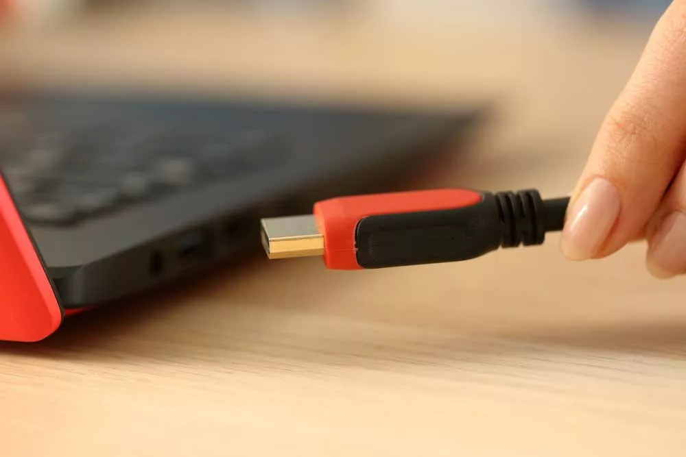A hand-plugging an HDMI cable into a laptop