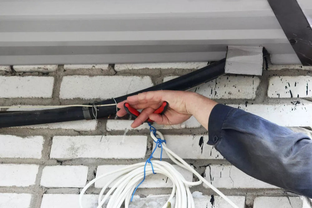 Electrician cutting a cable using a pair of wire cutters