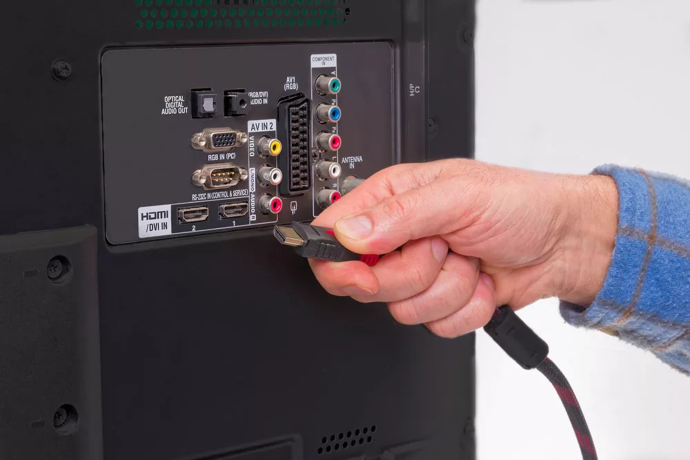 Hand-holding HDMI cable in the back of the HDTV box